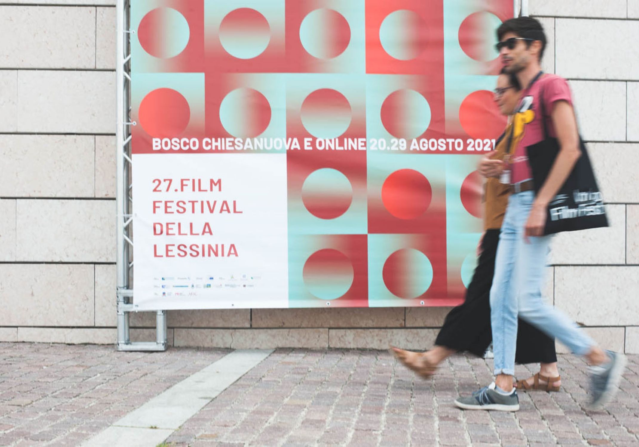 Persone passeggiano davanti al manifesto del Film Festival della Lessinia